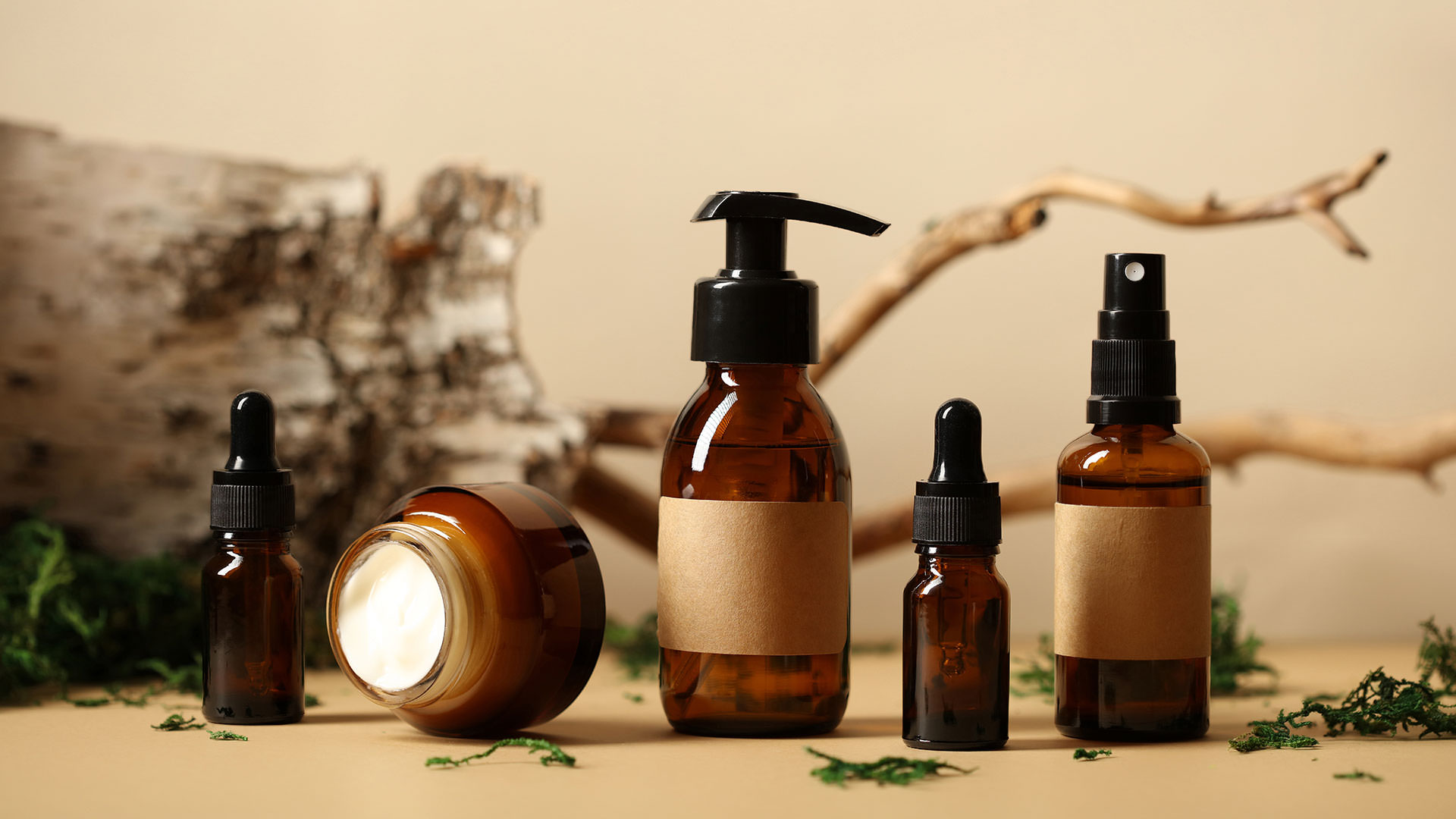 Collection of amber skincare bottles with brown labels set against a natural background.