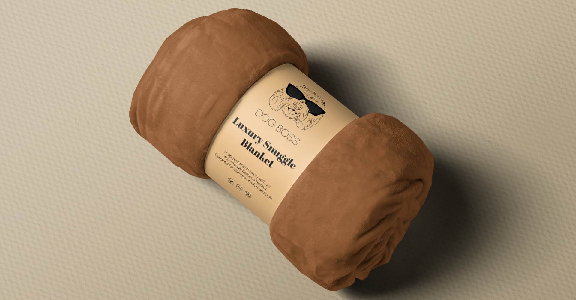 A rolled-up brown blanket with a label reading Dog Boss Luxury Snuggle Blanket, featuring a cartoon dog wearing sunglasses and additional product details, resting on a textured beige surface.