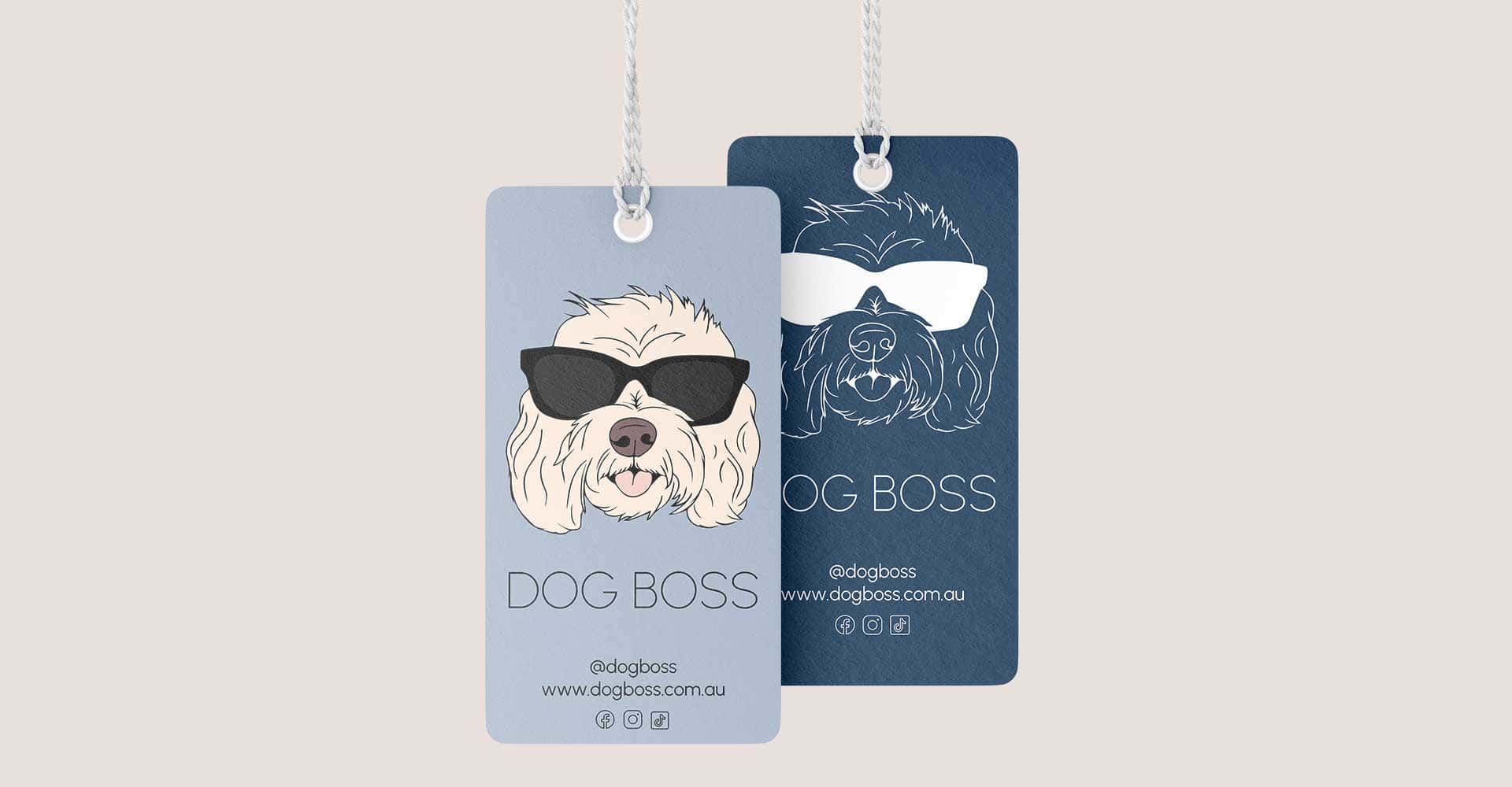 Two rectangular tags with illustrations of a dog wearing sunglasses, labeled DOG BOSS. One tag is blue with a white dog drawing, the other is light blue with a colored dog. Both include social media icons and website details.